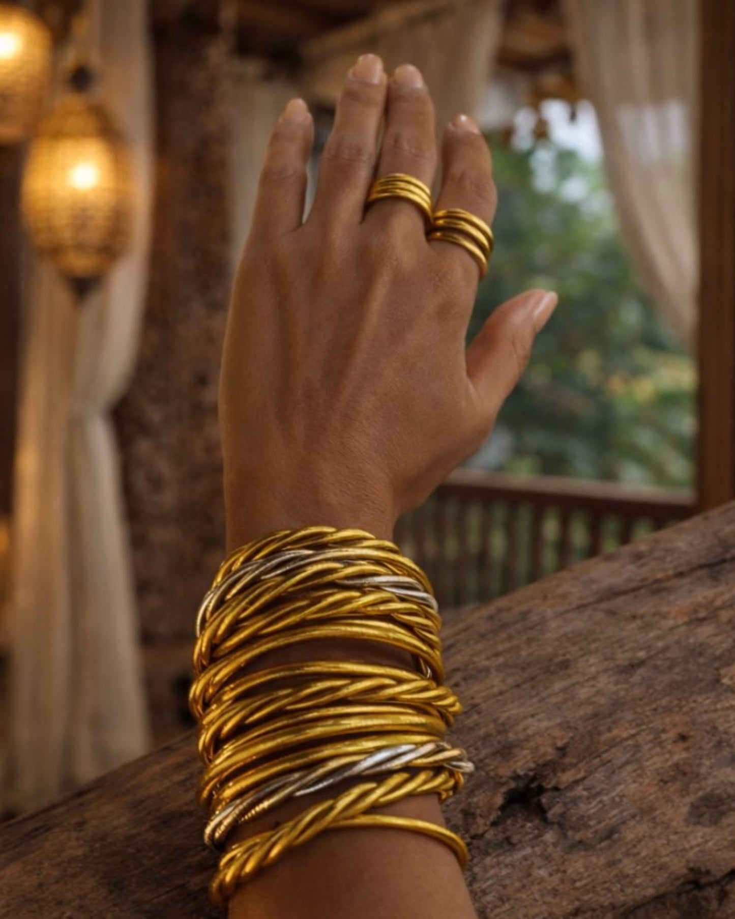 Bagues bouddhistes or Bâan Kumlaï portées avec bracelets Kumlaï dorés, accumulation élégante dans une ambiance premium