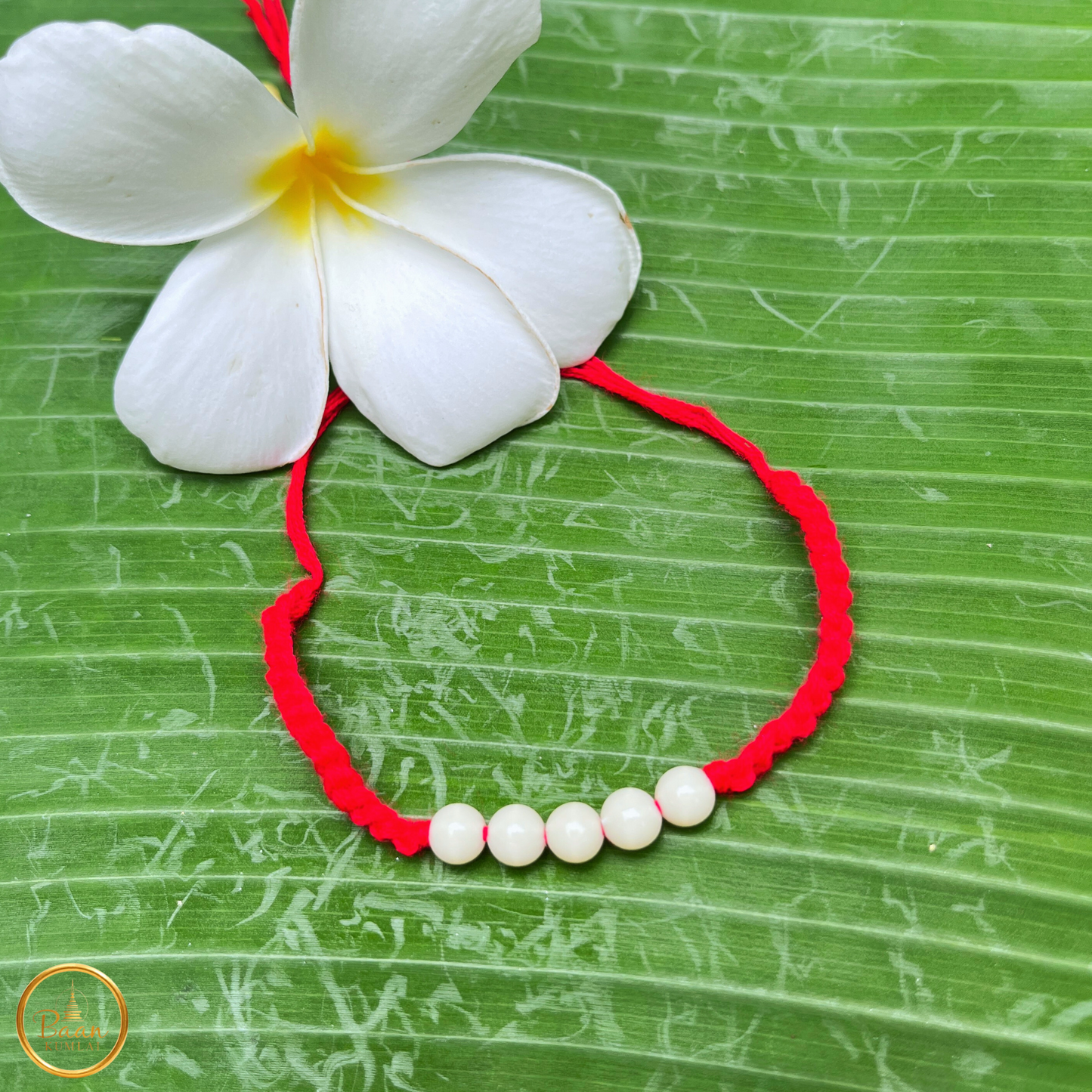Détail du bracelet rouge bouddhiste Sai Sin, fil porte-bonheur traditionnel bénit par les moines en Thaïlande.