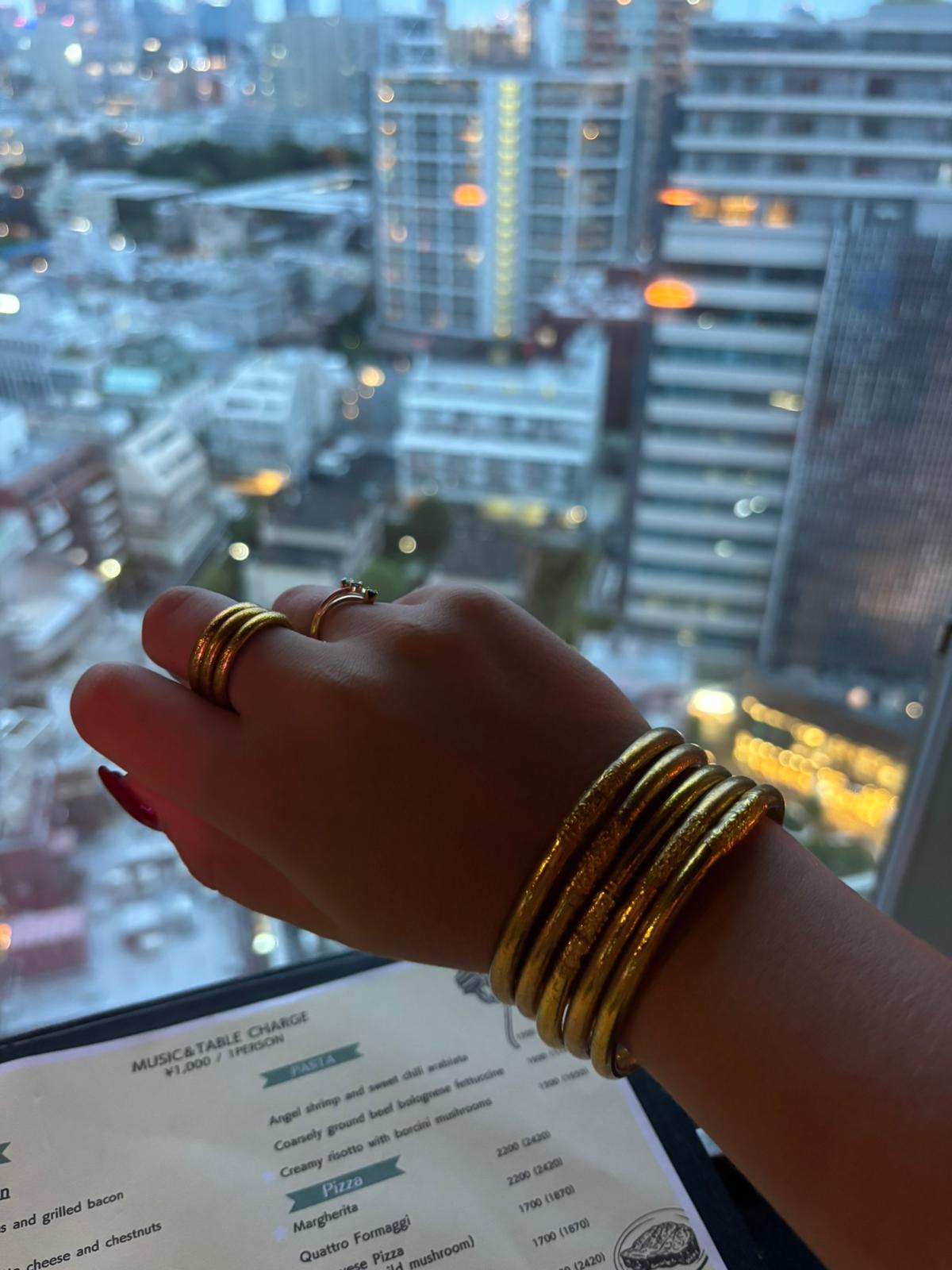 Trois bagues et cinq joncs bouddhistes or au poignet d’une cliente Baan Kumlaï  – Bijoux bénis pour chance et prospérité
