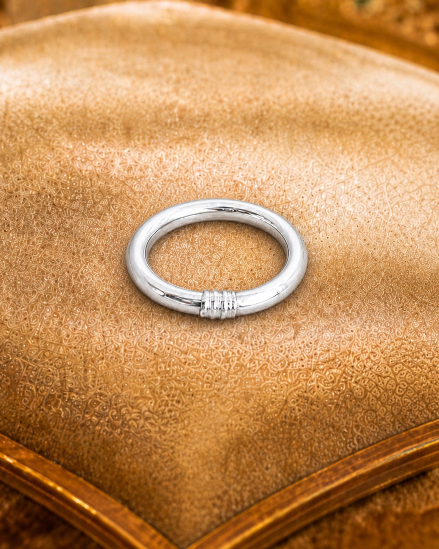 Détail d’une bague bouddhiste argent Bâan Kumlaï posée sur coussin beige, avec finition argent brillante.