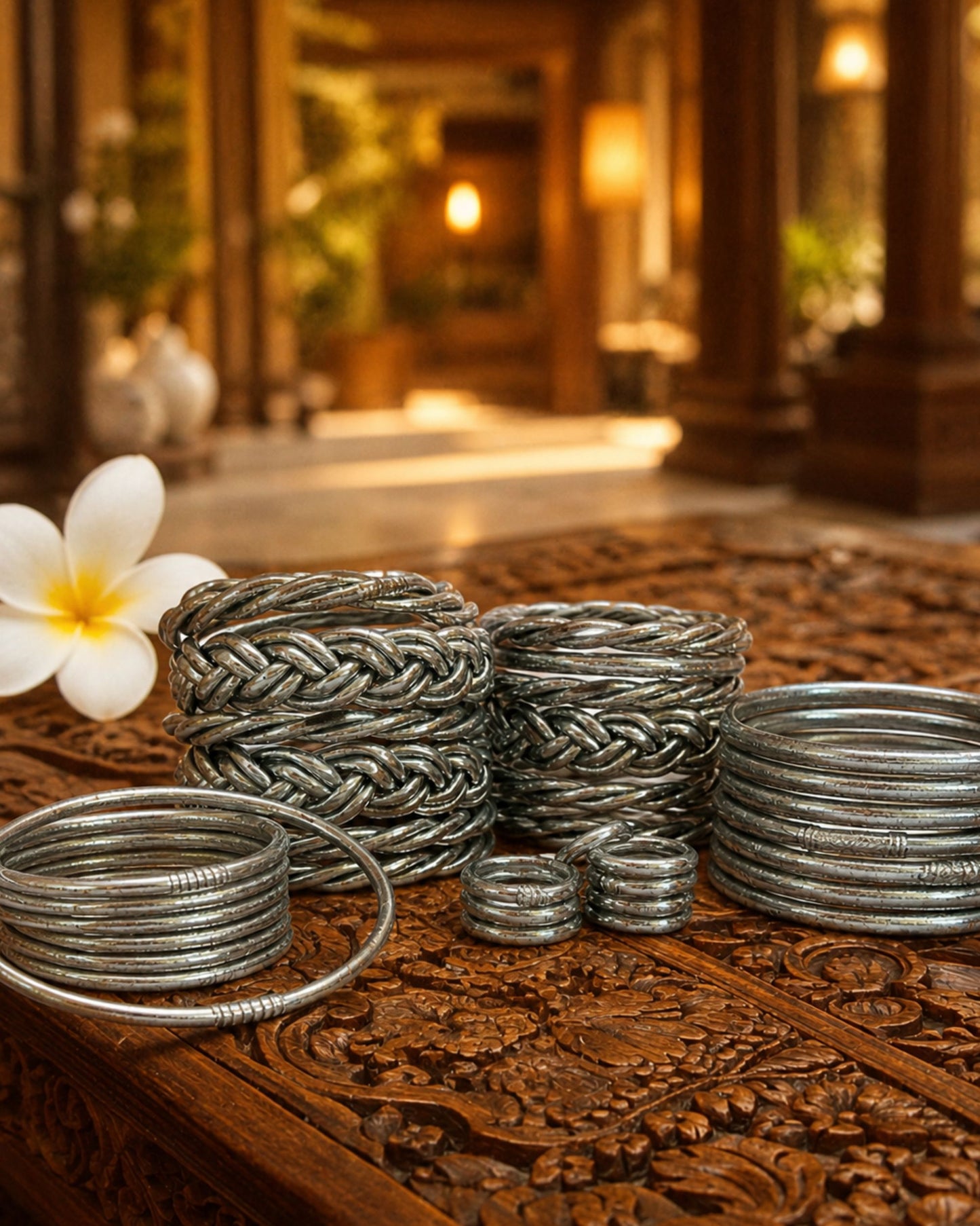 Collection de bagues bouddhistes argent et bracelets Kumlai argent Bâan Kumlaï sur table en bois sculpté