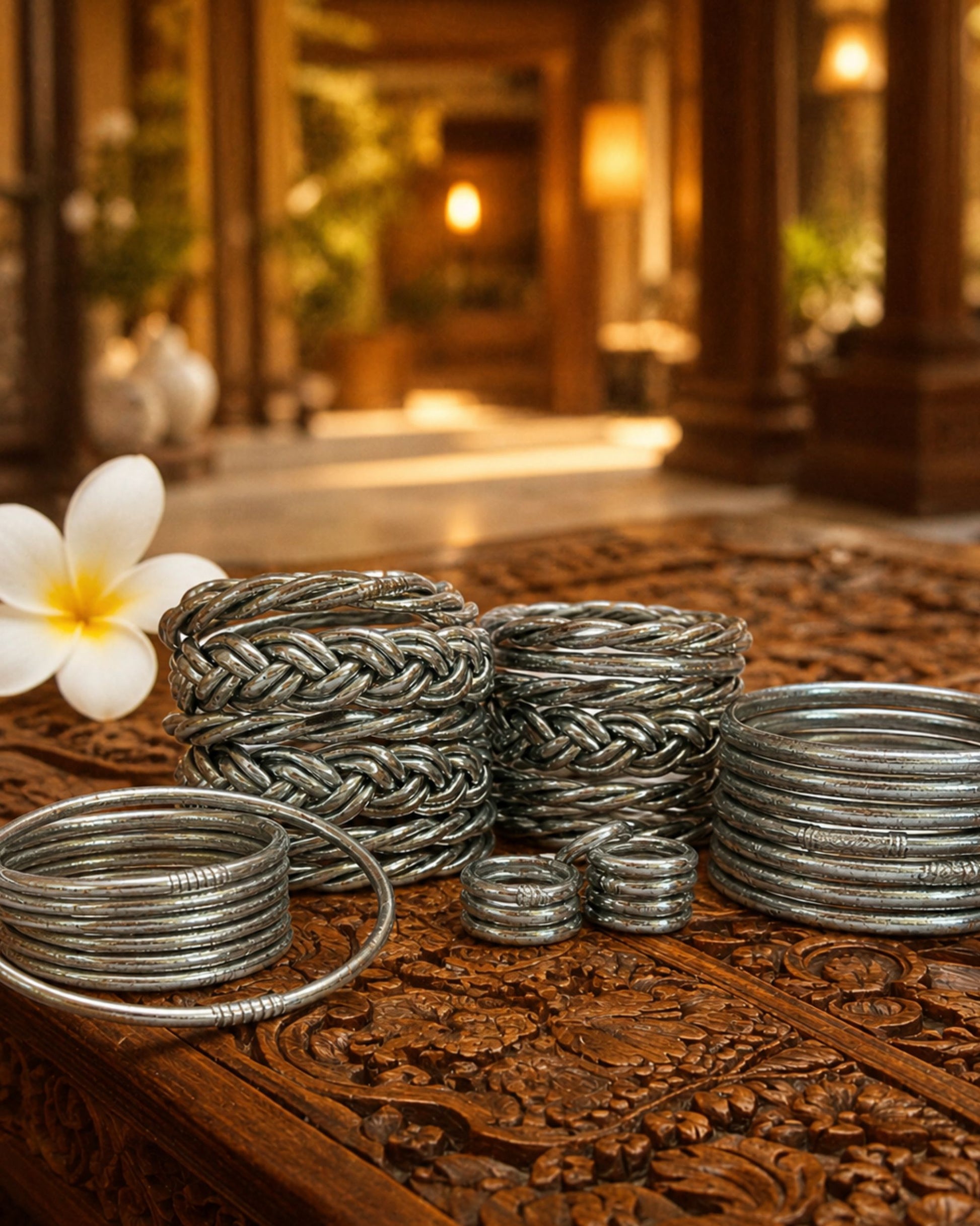Collection de bagues bouddhistes argent et bracelets Kumlai argent Bâan Kumlaï sur table en bois sculpté