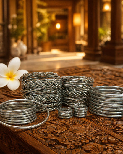 Collection de bagues bouddhistes argent et bracelets Kumlai argent Bâan Kumlaï sur table en bois sculpté