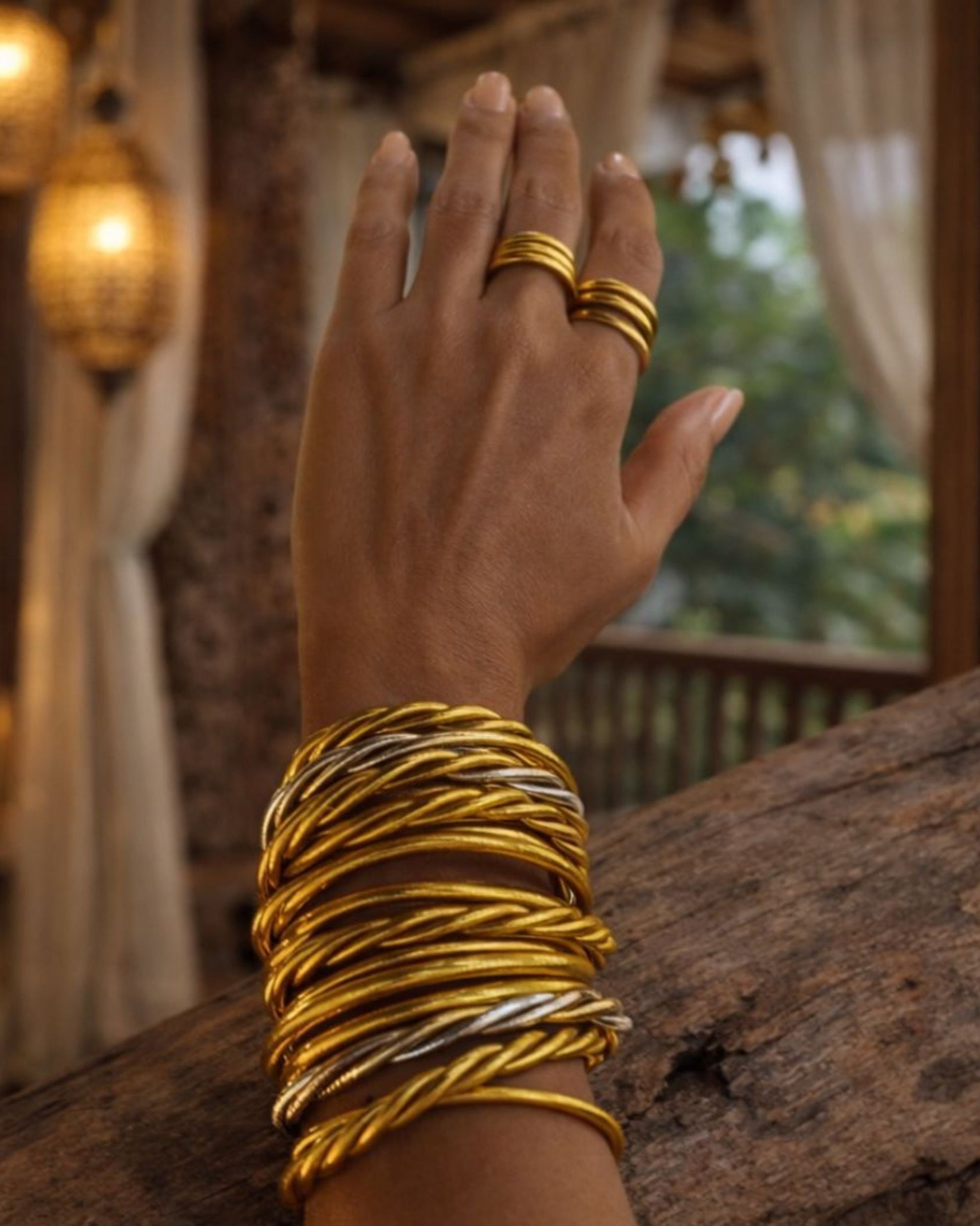Bagues bouddhistes or Bâan Kumlaï portées avec bracelets Kumlaï dorés, accumulation élégante dans une ambiance premium