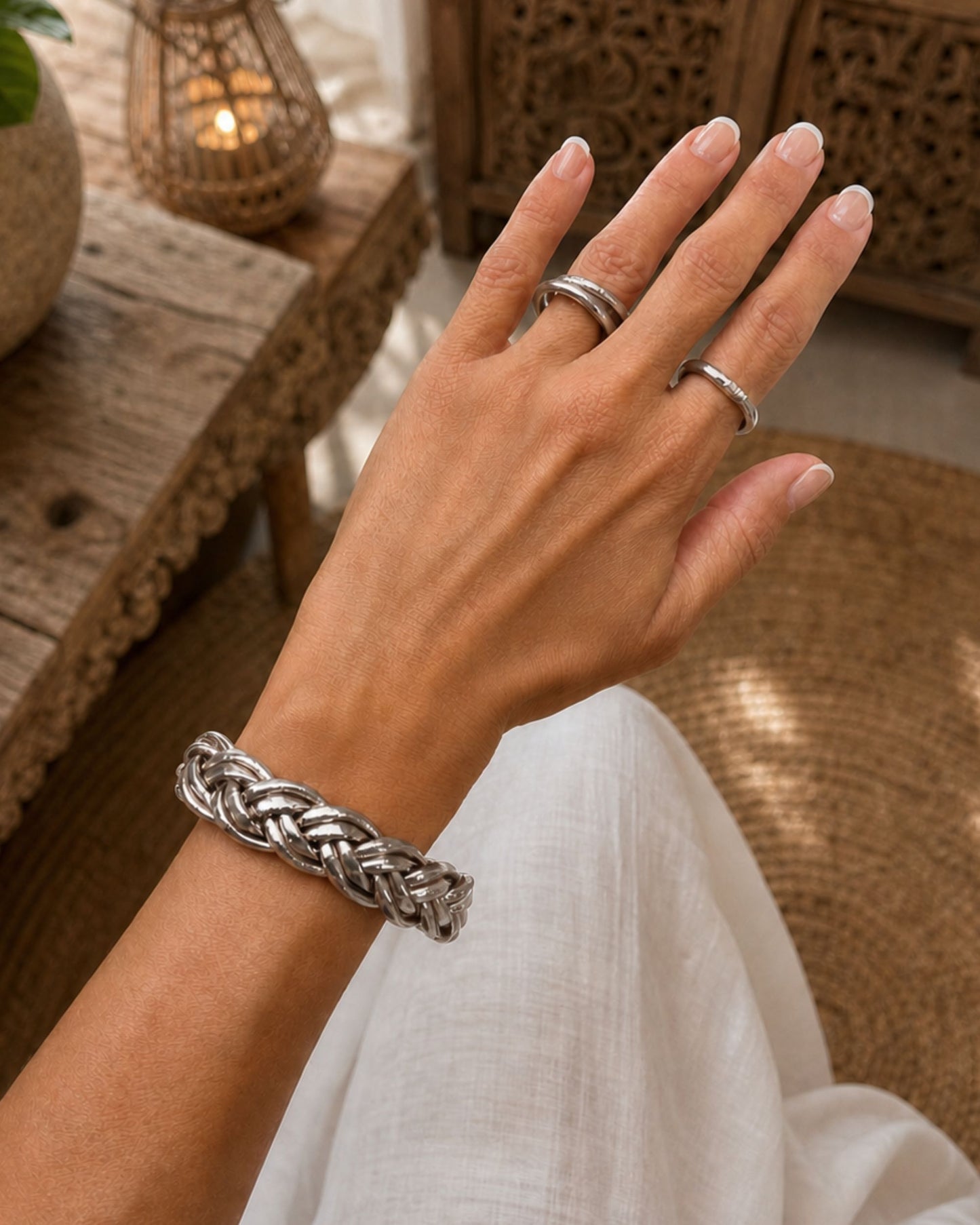 Bague Kumlai argent portée à la main avec bracelet tressé argent Bâan Kumlaï dans un univers naturel et élégant