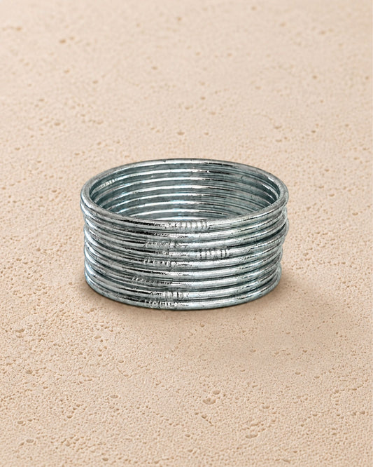 Accumulation de joncs bouddhistes argent fins Bâan Kumlaï sur fond minéral chaud, Kumlai argent fabriqués en Thaïlande