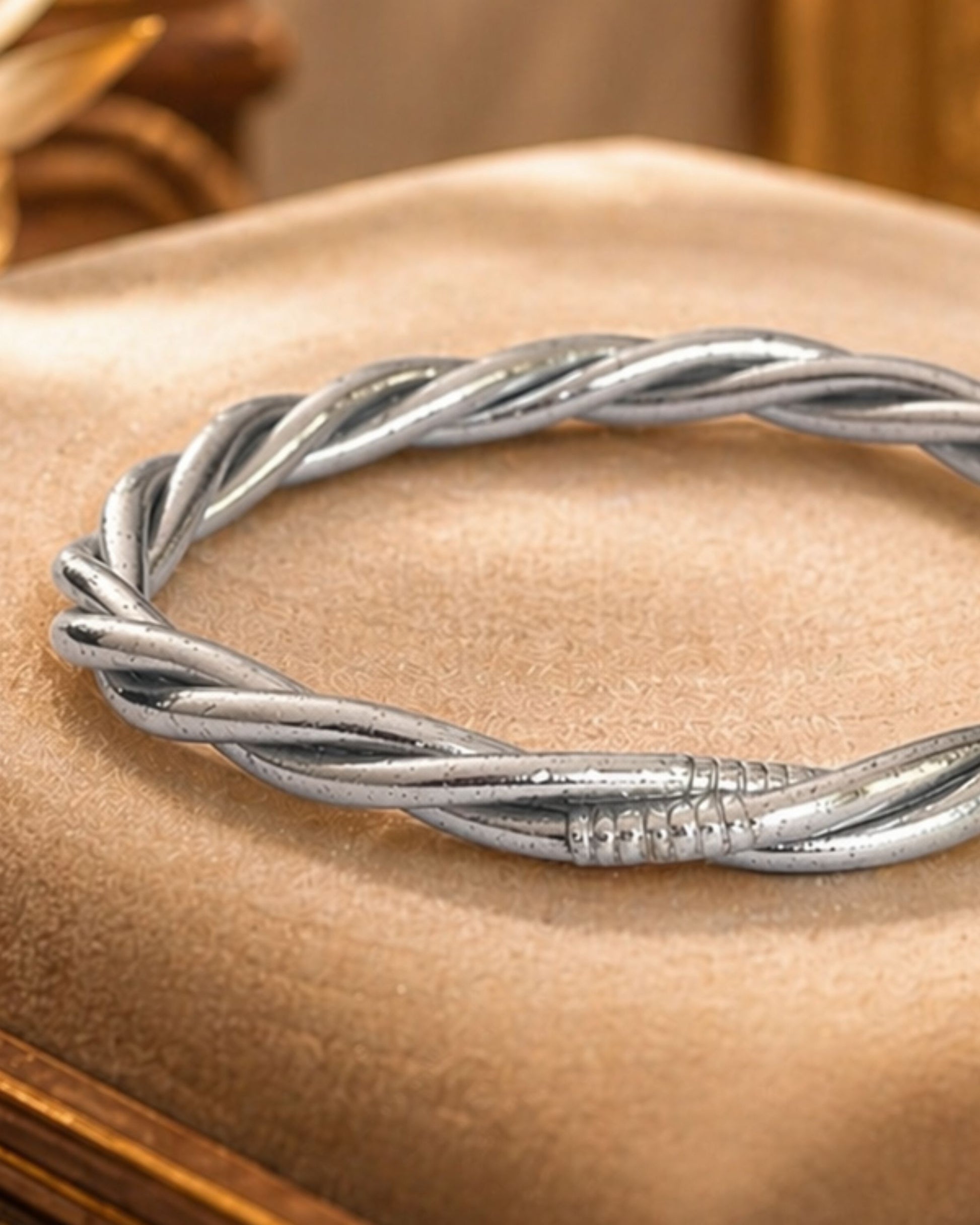 Détail du jonc bouddhiste argent torsadé Bâan Kumlaï, bracelet bouddhiste argenté sur coussin beige premium