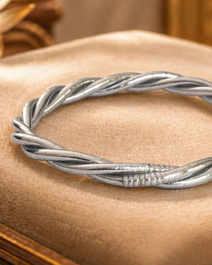 Détail du jonc bouddhiste argent torsadé Bâan Kumlaï, bracelet bouddhiste argenté sur coussin beige premium