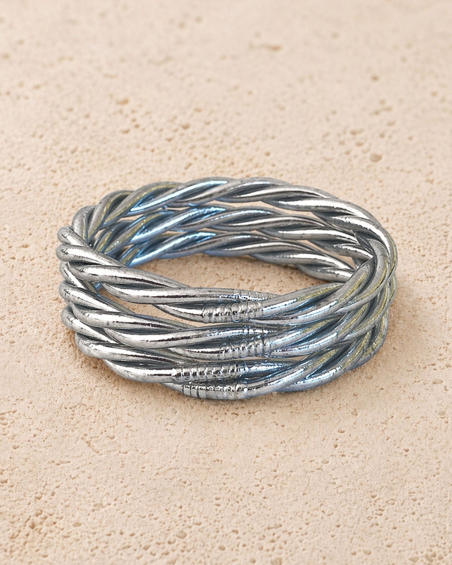 Jonc bouddhiste argent torsadé Bâan Kumlaï sur fond minéral chaud, bracelet Kumlai argenté fabriqué en Thaïlande