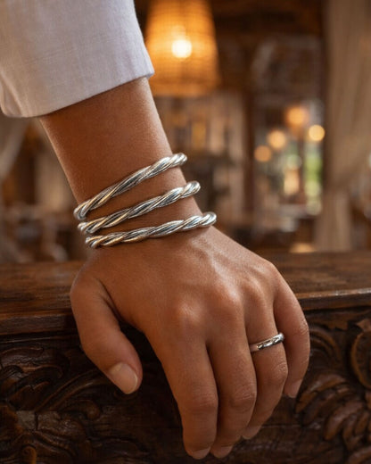 Bracelet bouddhiste argent torsadé Bâan Kumlaï porté à la main sur bois sculpté, bracelet Kumlai argenté élégant