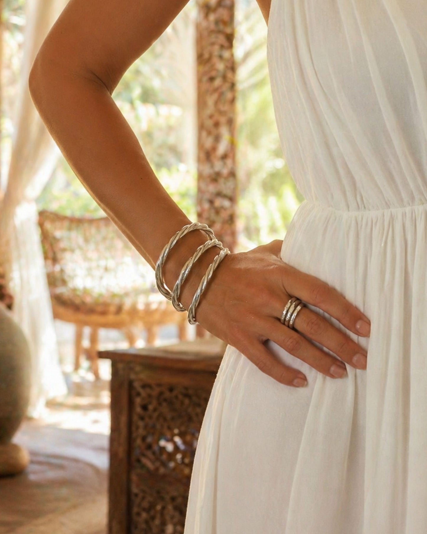 Jonc bouddhiste argent torsadé Bâan Kumlaï porté au poignet avec robe blanche, bracelet Kumlai argent élégant