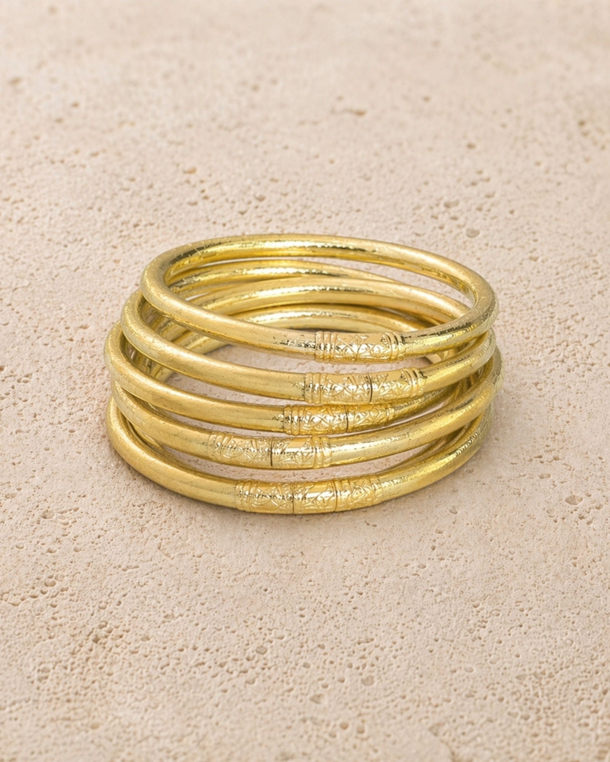 Accumulation de 5 joncs bouddhistes champagne Bâan Kumlaï avec mantra visible sur fond minéral chaud
