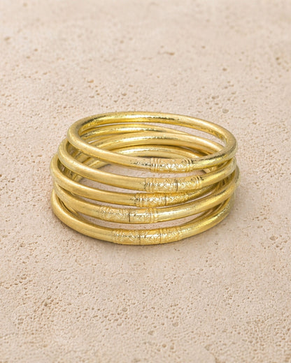 Accumulation de 5 joncs bouddhistes champagne Bâan Kumlaï avec mantra visible sur fond minéral chaud