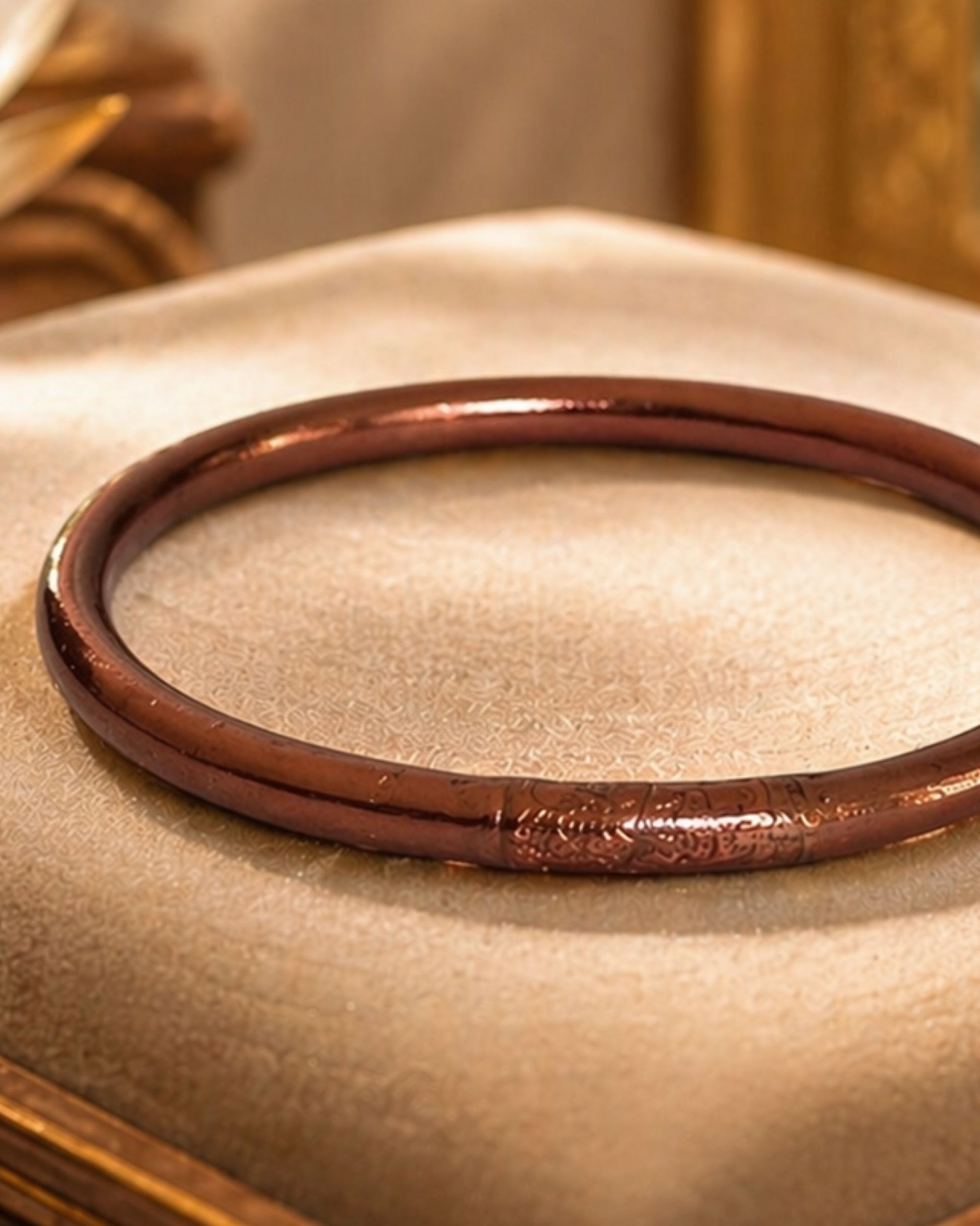 Détail du jonc bouddhiste chocolat Bâan Kumlaï avec mantra gravé, bracelet Kumlai marron posé sur coussin beige