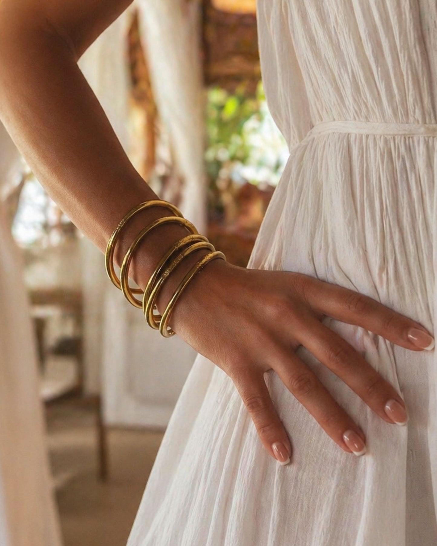 Joncs bouddhistes or antique Bâan Kumlaï portés avec une robe blanche, look féminin et lumineux