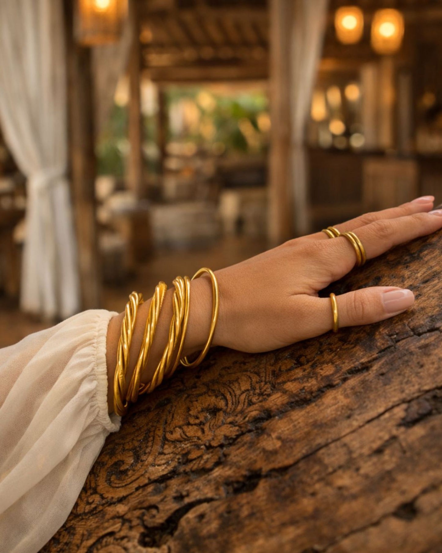 Accumulation de bracelets joncs bouddhistes or fins Bâan Kumlaï portés au poignet avec bagues Kumlai assorties