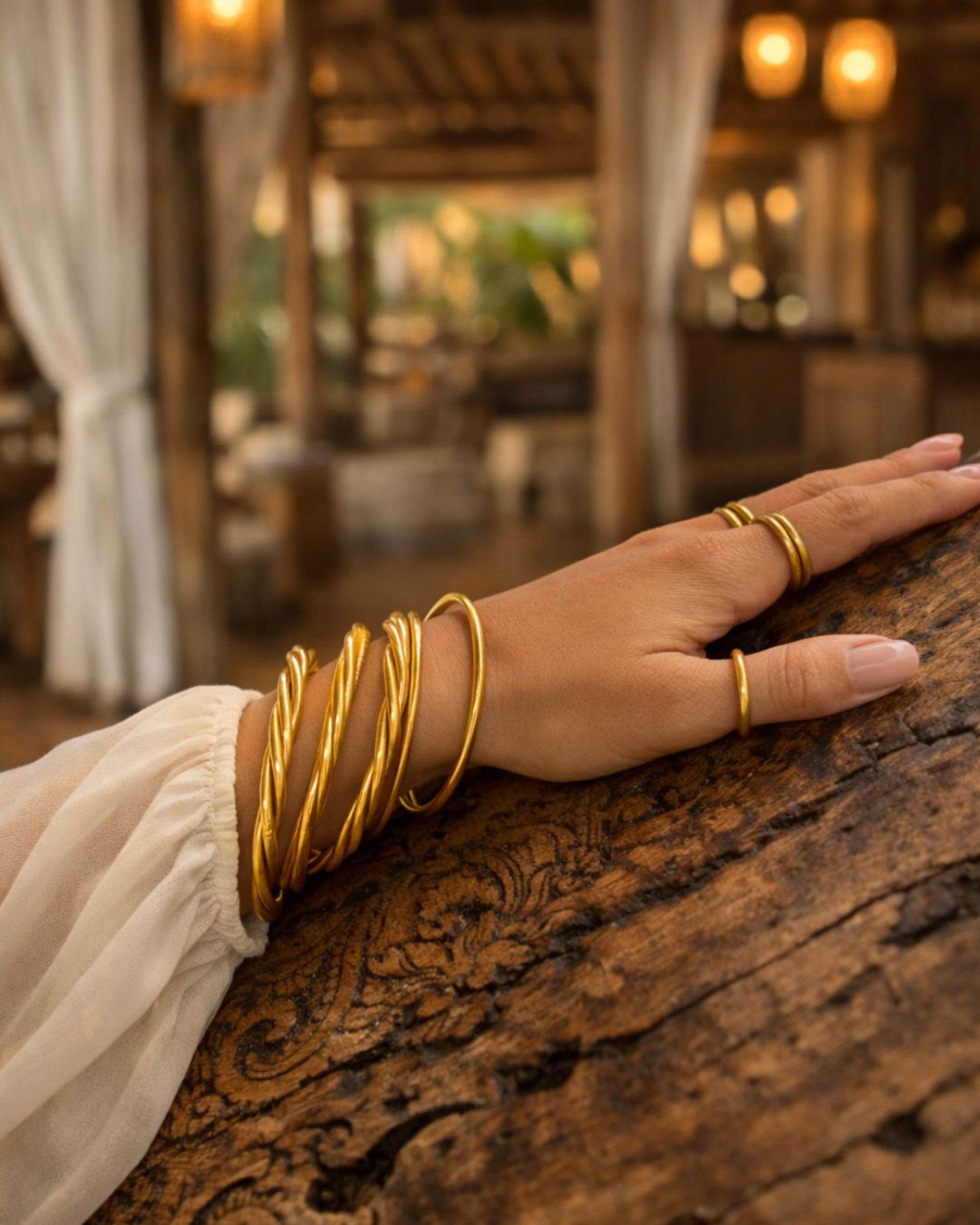 Accumulation de bracelets joncs bouddhistes or fins Bâan Kumlaï portés au poignet avec bagues Kumlai assorties