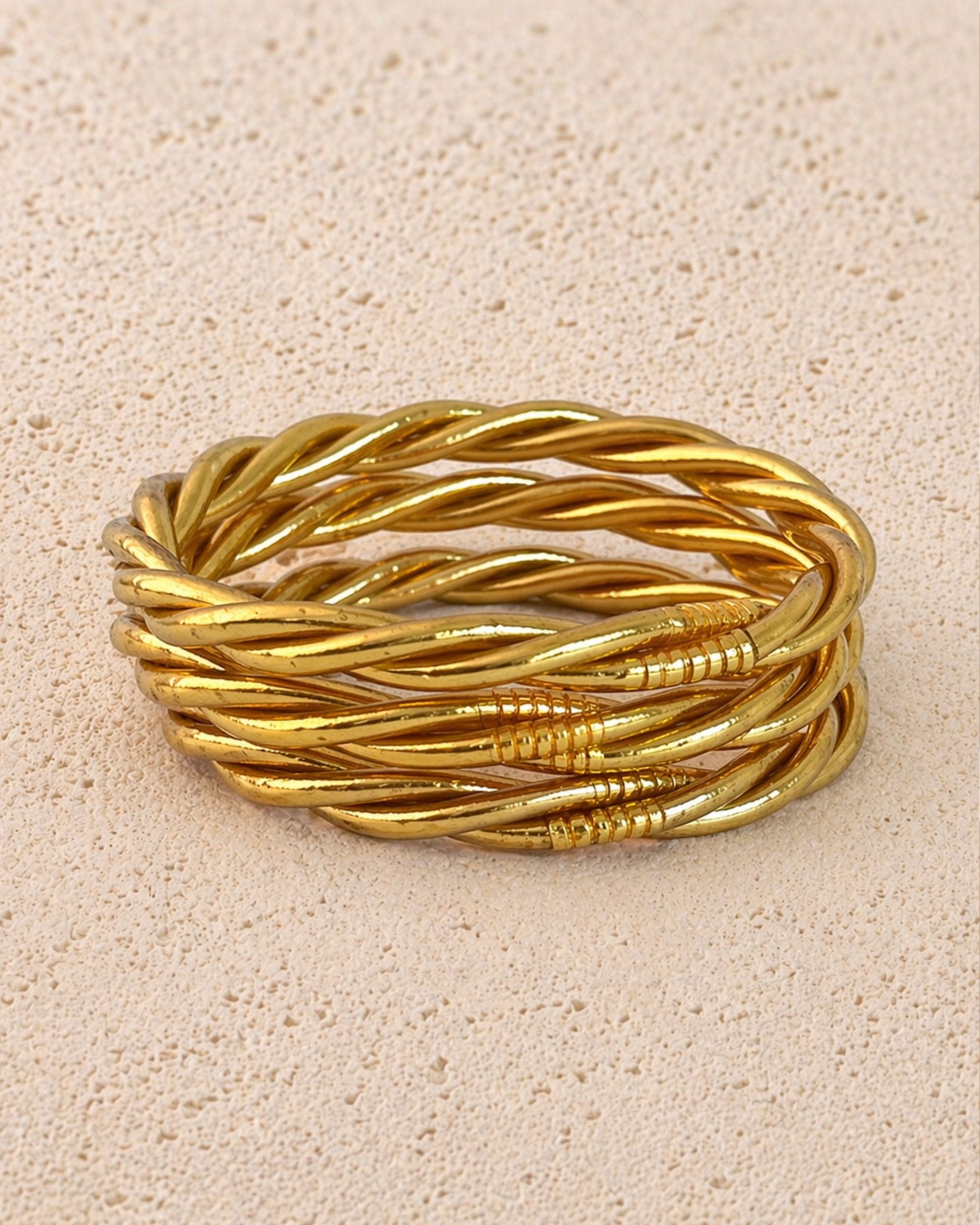 Jonc bouddhiste or torsadé Bâan Kumlaï sur fond minéral chaud, bracelet Kumlai doré fabriqué en Thaïlande