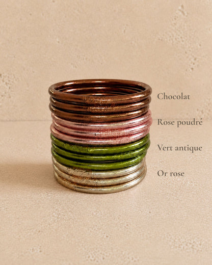 Accumulation de bracelets Kumlai Bâan Kumlaï avec jonc bouddhiste vert antique, rose poudré, chocolat et or rose.