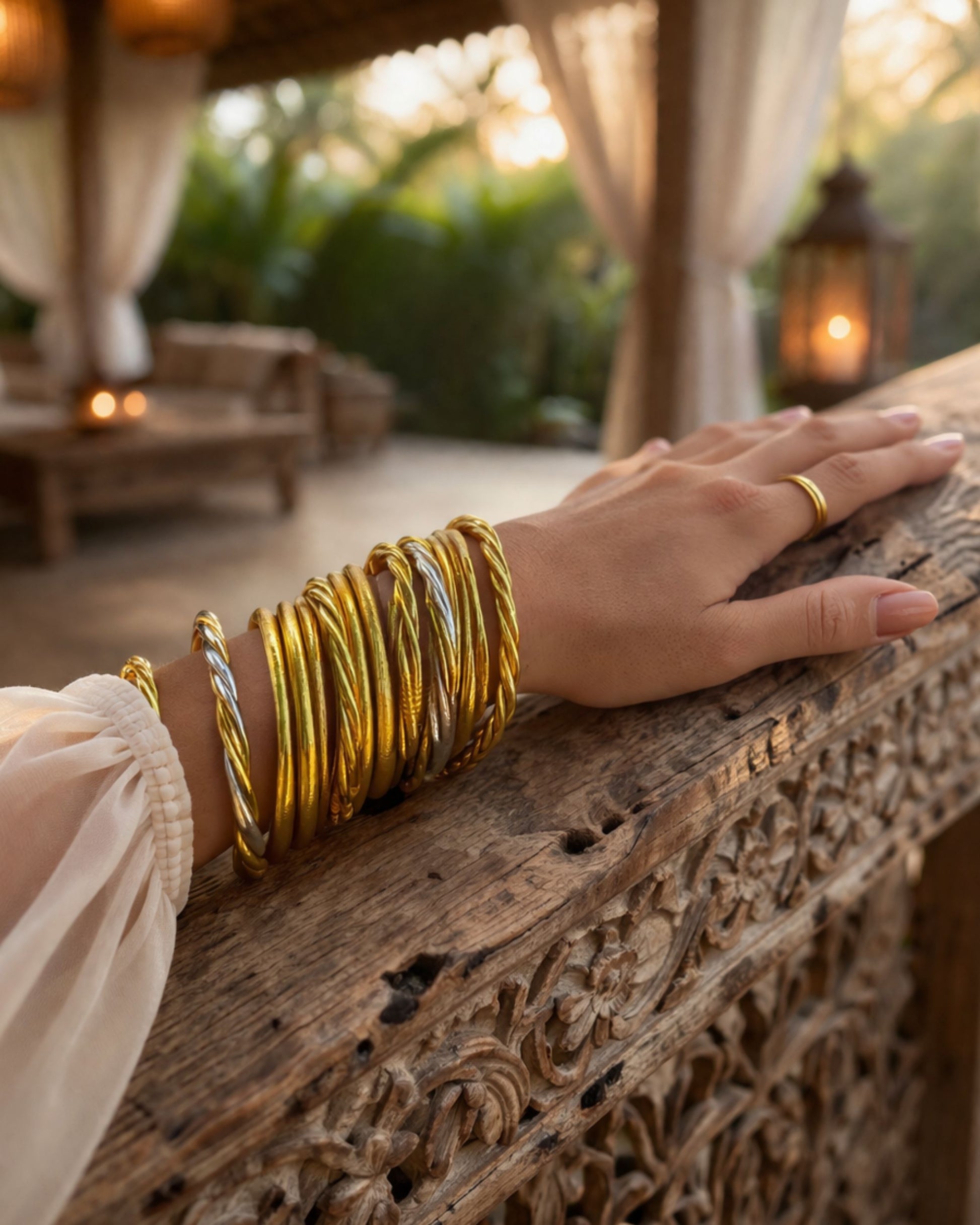 Accumulation de joncs bouddhistes Bâan Kumlaï sur bras posé sur une rampe en bois, avec bracelets or, torsadé or et torsadé 3 couleurs