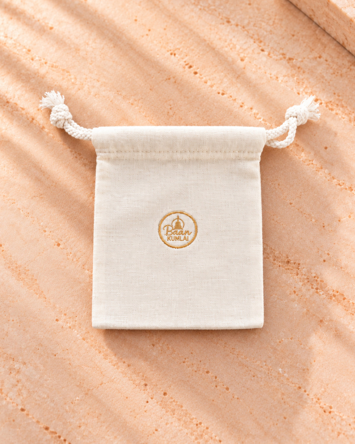 Pochette cadeau en lin crème Bâan Kumlaï, avec logo brodé au fil doré, confectionnée à Koh Samui en Thaïlande.