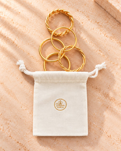 Pochon cadeau Bâan Kumlaï en tissu crème avec assortiment de bracelets bouddhistes fins, torsadés et tressés dorés.