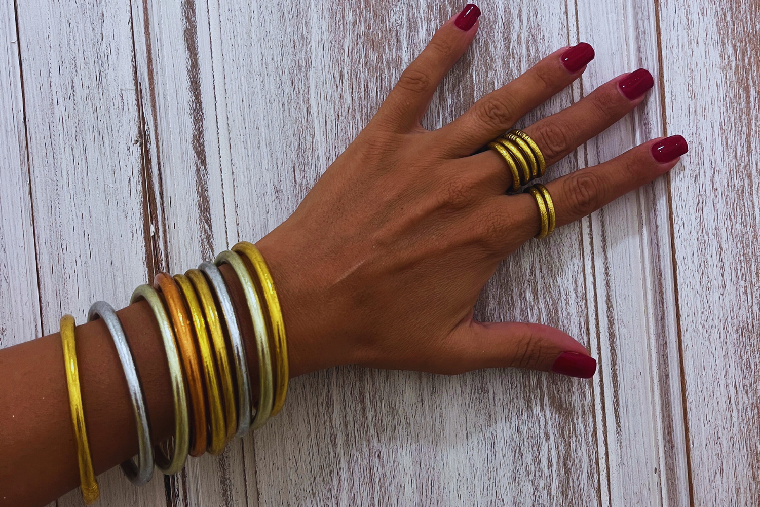 Main portant une accumulation de joncs bouddhistes Kumlaï de différentes couleurs.